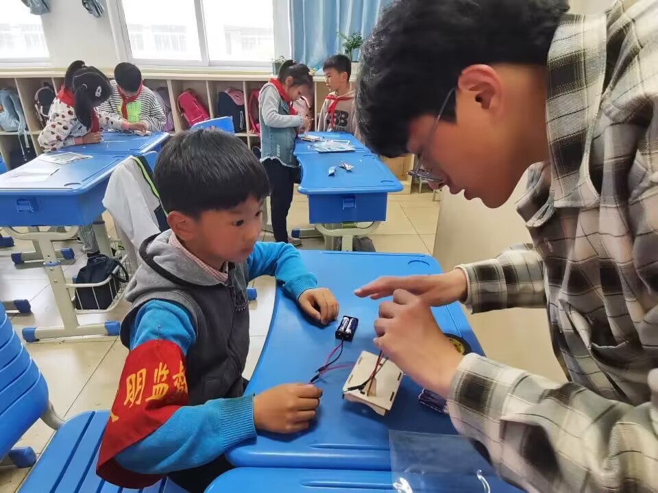 图为乐竞在线平台(中国)官网自动化学院志愿者蔡志锦帮助润商小学二年级一班同学连接电路.jpg